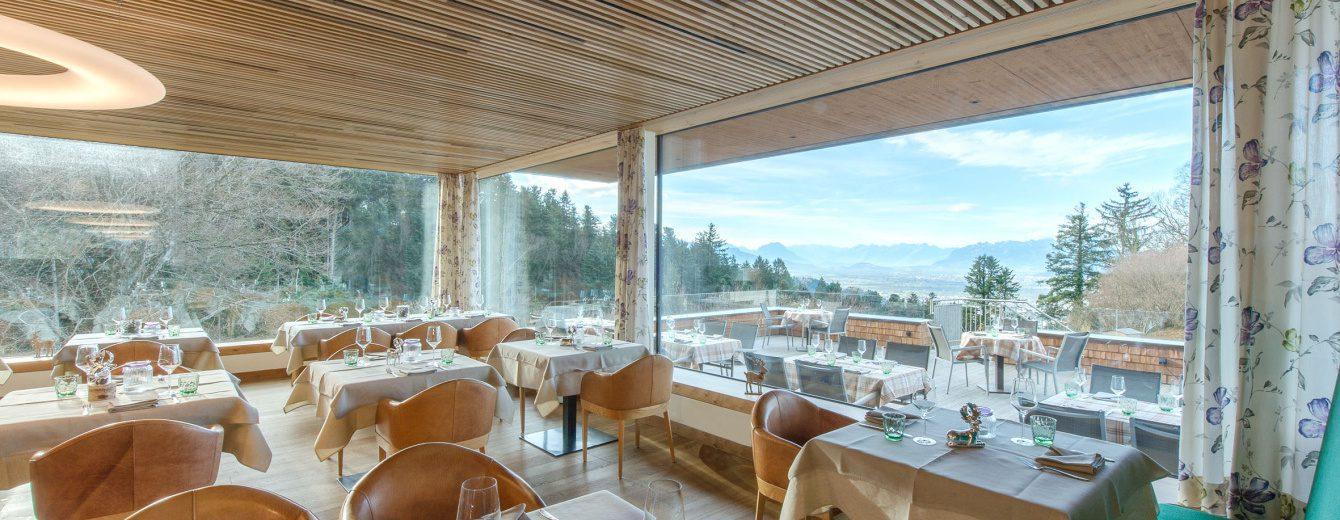 Einblick in den Essbereich eines Restaurants mit großer Fensterfront uns Ausblick auf die Berge