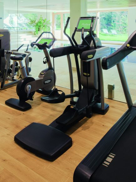 Modern ausgestatteter Fitnessraum mit Laufbändern und Trainingsgeräten und großen Glasfenstern