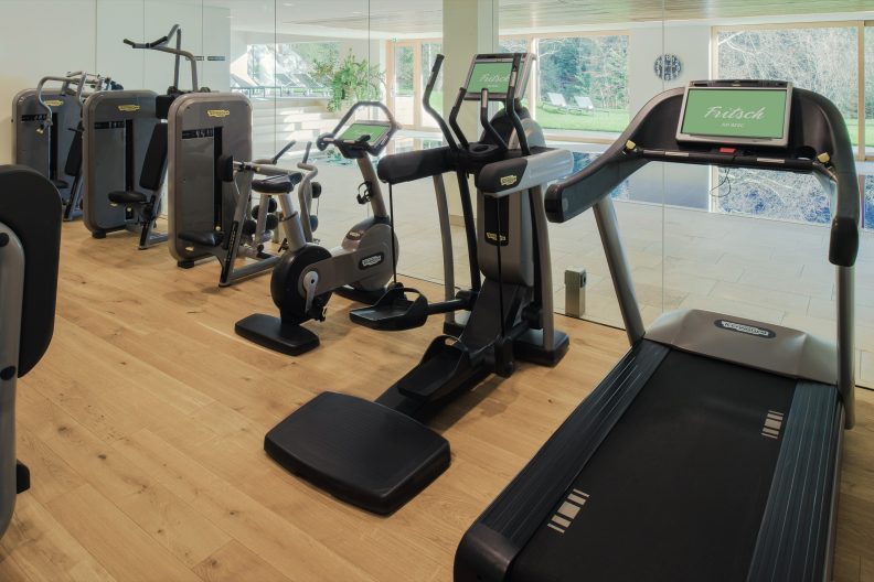 Modern ausgestatteter Fitnessraum mit Laufbändern und Trainingsgeräten und großen Glasfenstern
