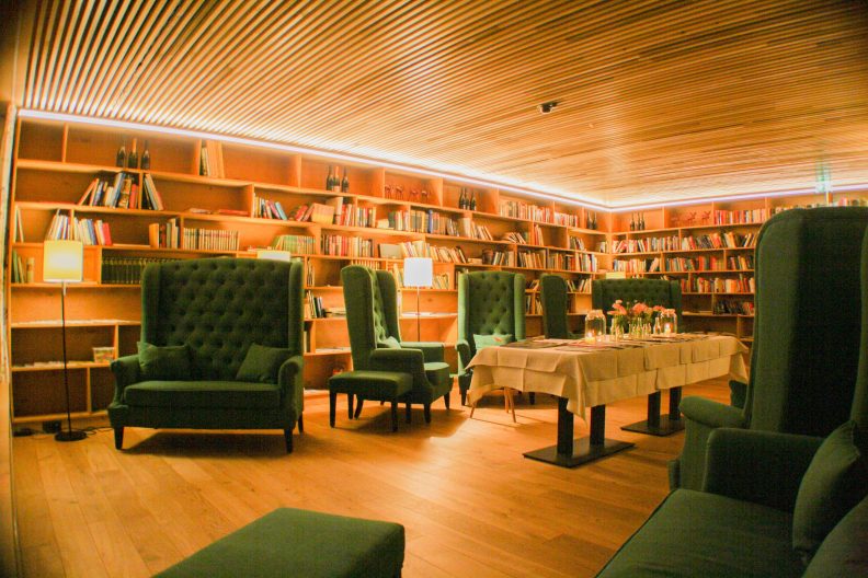 Einblick in die gemütliche Bibliothek mit bequemen grünen Sesseln