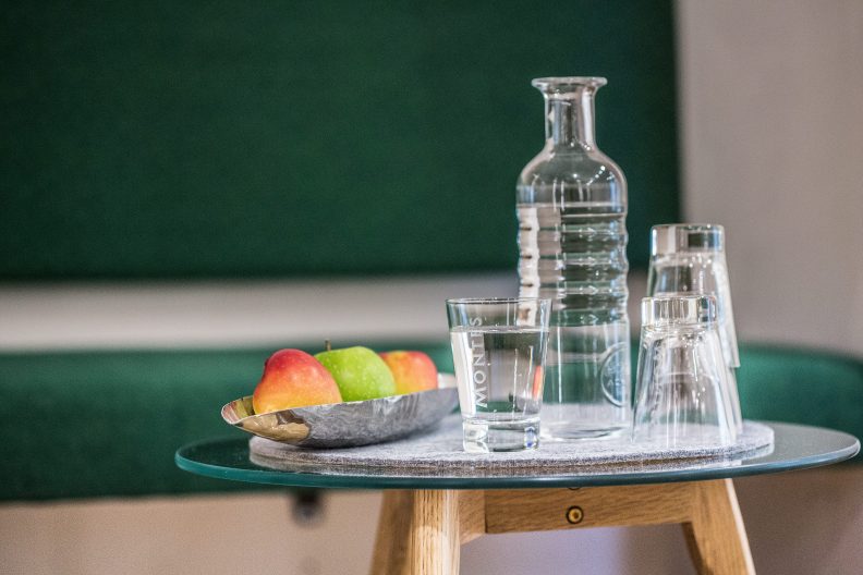 Detailaufnahme eines kleines Tischchens mit einer Obstschale, Gläsern und einer Karaffe gefüllt mit Wasser