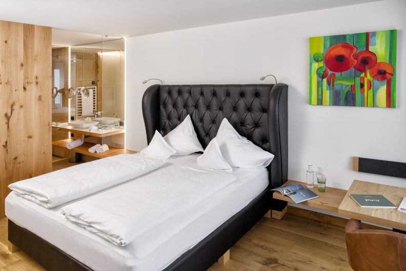 Einblick in ein Zimmer mit einem schwarzen Doppelbett aus Leder