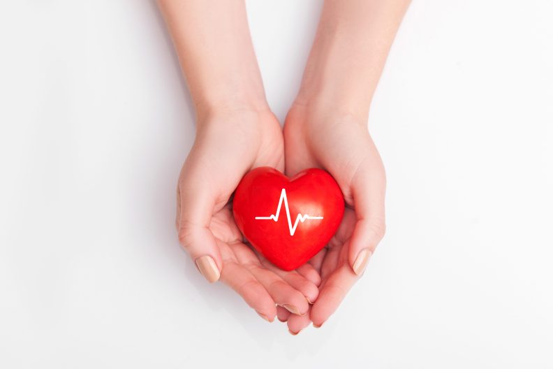 Detailaufnahme von Menschenhänden welche ein rotes Herz halten