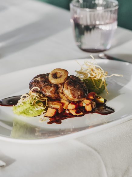 Ein kunstvoll angerichtetes Gourmetgericht mit Fleisch, Gemüse und Sauce im Restaurant in Lochau