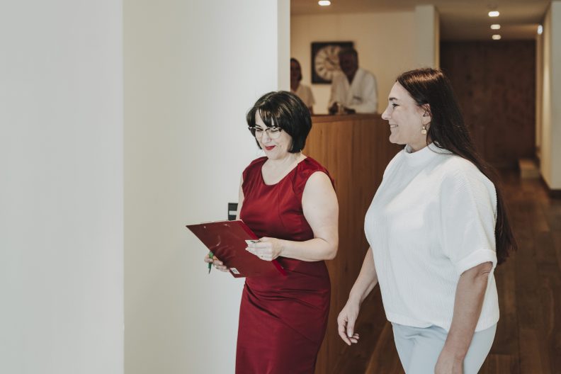 Zwei Frauen unterhalten sich freundlich in einem Hotelgang in einem Hotel am Bodensee mit Seeblick