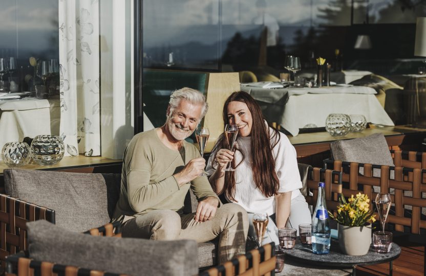 Ein älteres Paar genießt gemeinsam Sekt im Freien und strahlt Freude und Entspannung aus
