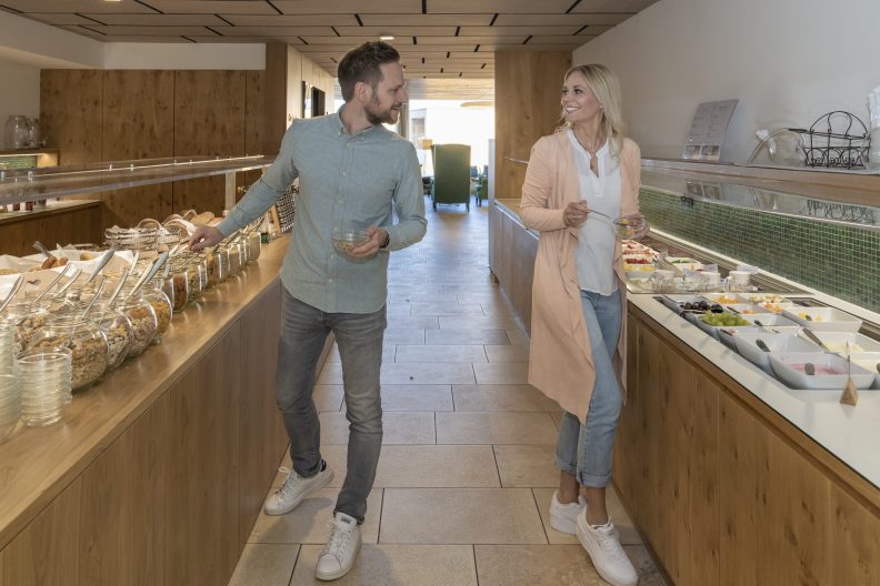 Ein Paar füllt sich Schalen am Frühstücksbuffet eines Hotels vor einem Day Spa Tag am Bodensee