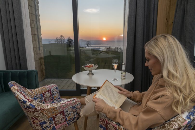 Eine Frau genießt ein Wellness Arrangement am Bodensee mit einem Buch und ein Glas Sekt