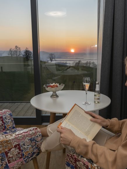 Eine Frau genießt ein Wellness Arrangement am Bodensee mit einem Buch und ein Glas Sekt