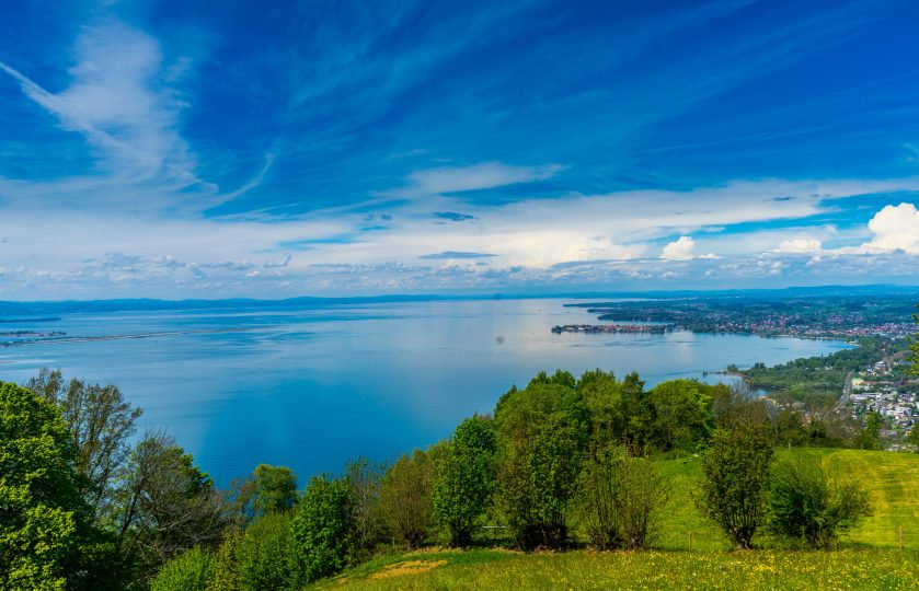 Blick auf den Bodensee an einem klaren Tag und grünen Bäumen von einem Hotel am Bodensee mit Seeblick